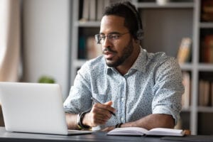 Focused African-American Student Wears Headphones Study Online Watchin